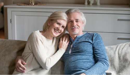 Older couple smiling on a couch